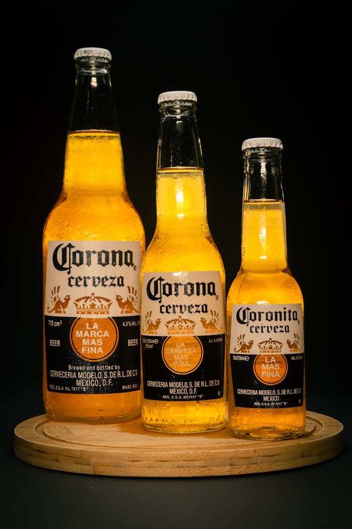 Three Corona beer bottles on a wooden chopping board against a black background.