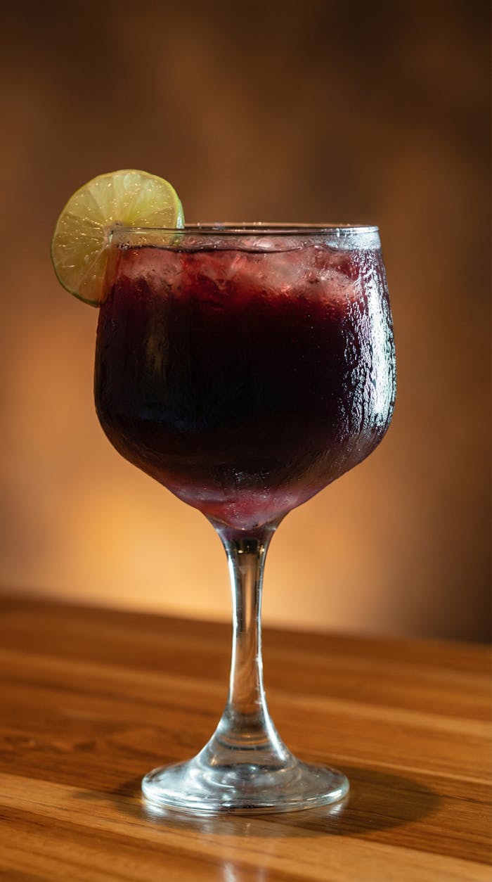 Close-up of a refreshing sangria cocktail garnished with lime on a wooden table in Colombia.